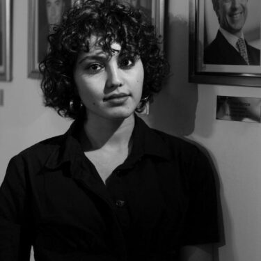 free-photo-of-a-woman-posing-against-portraits-hanging-on-the-wall